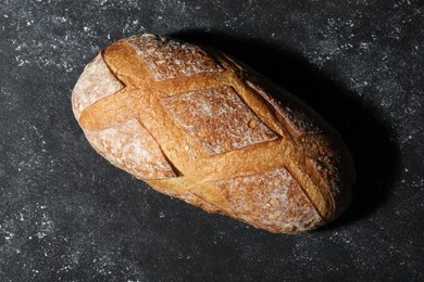 Photo of Loaf of fresh bread on grey textured table, top view