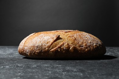 Photo of Loaf of fresh bread on grey textured table, closeup