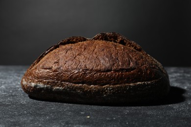 Photo of Loaf of fresh bread on grey textured table, closeup