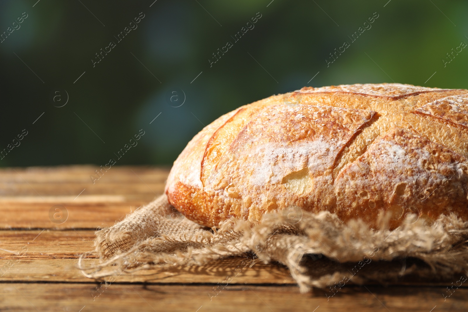 Loaf of fresh bread on wooden table against blurred background, closeup. Space for text Photo of Loaf of fresh bread on wooden table against blurred background, closeup. Space for text