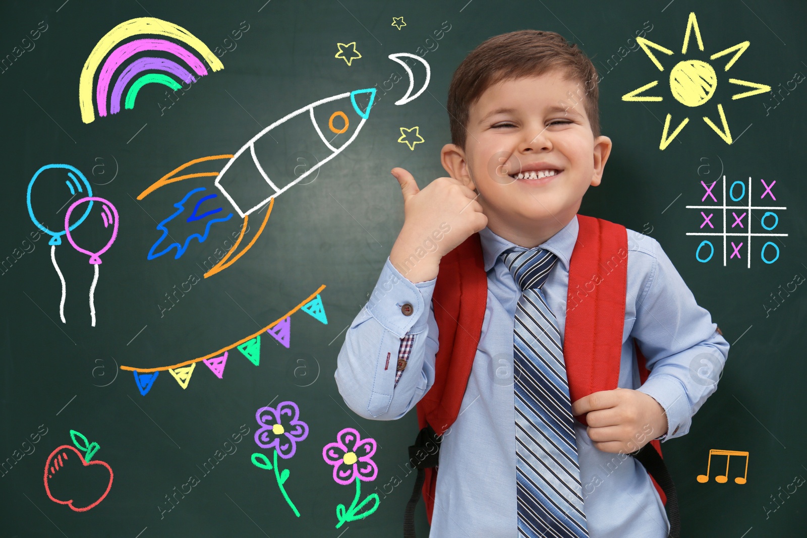 Child showing thumbs-up near green chalkboard with drawings Image of Child showing thumbs-up near green chalkboard with drawings