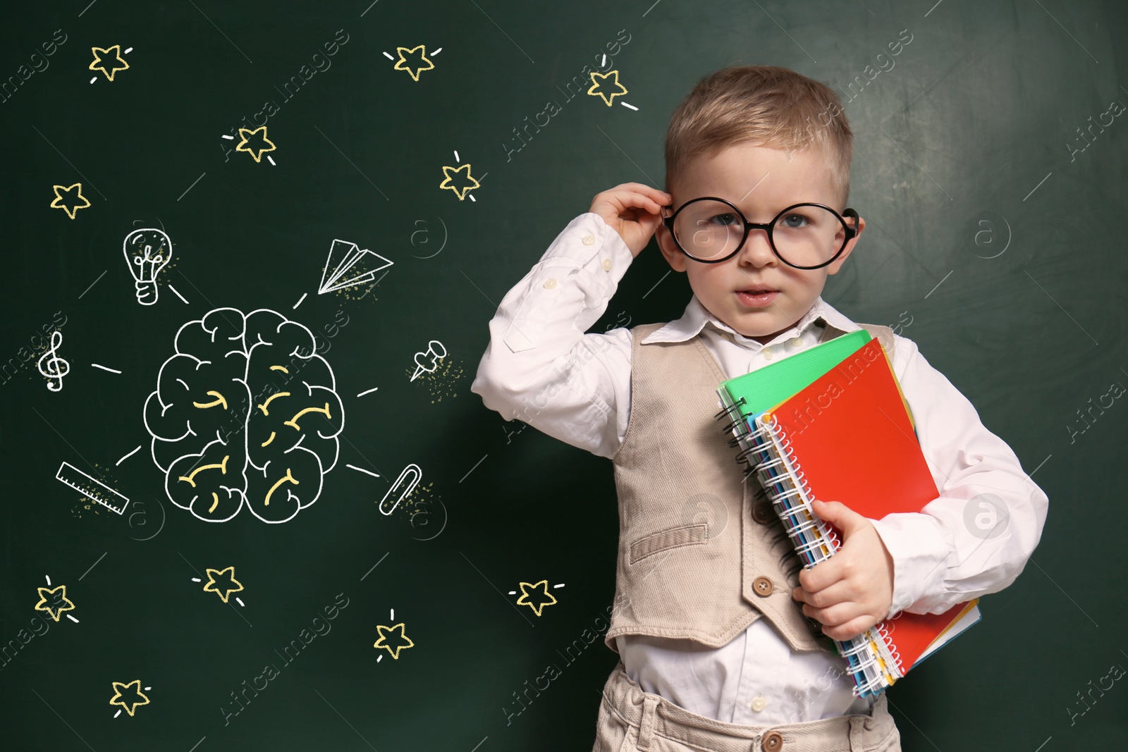 Image of Child wearing eyeglasses near green chalkboard with drawings