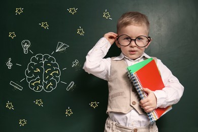 Image of Child wearing eyeglasses near green chalkboard with drawings