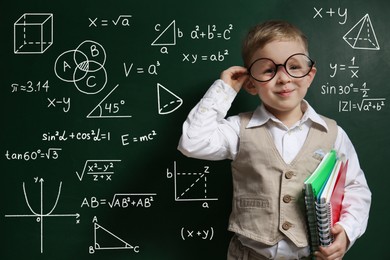 Image of Child wearing eyeglasses near green chalkboard with formulas and drawings
