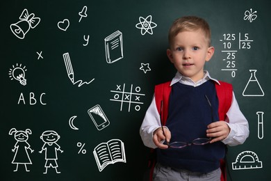 Image of Child holding eyeglasses near chalkboard with drawings