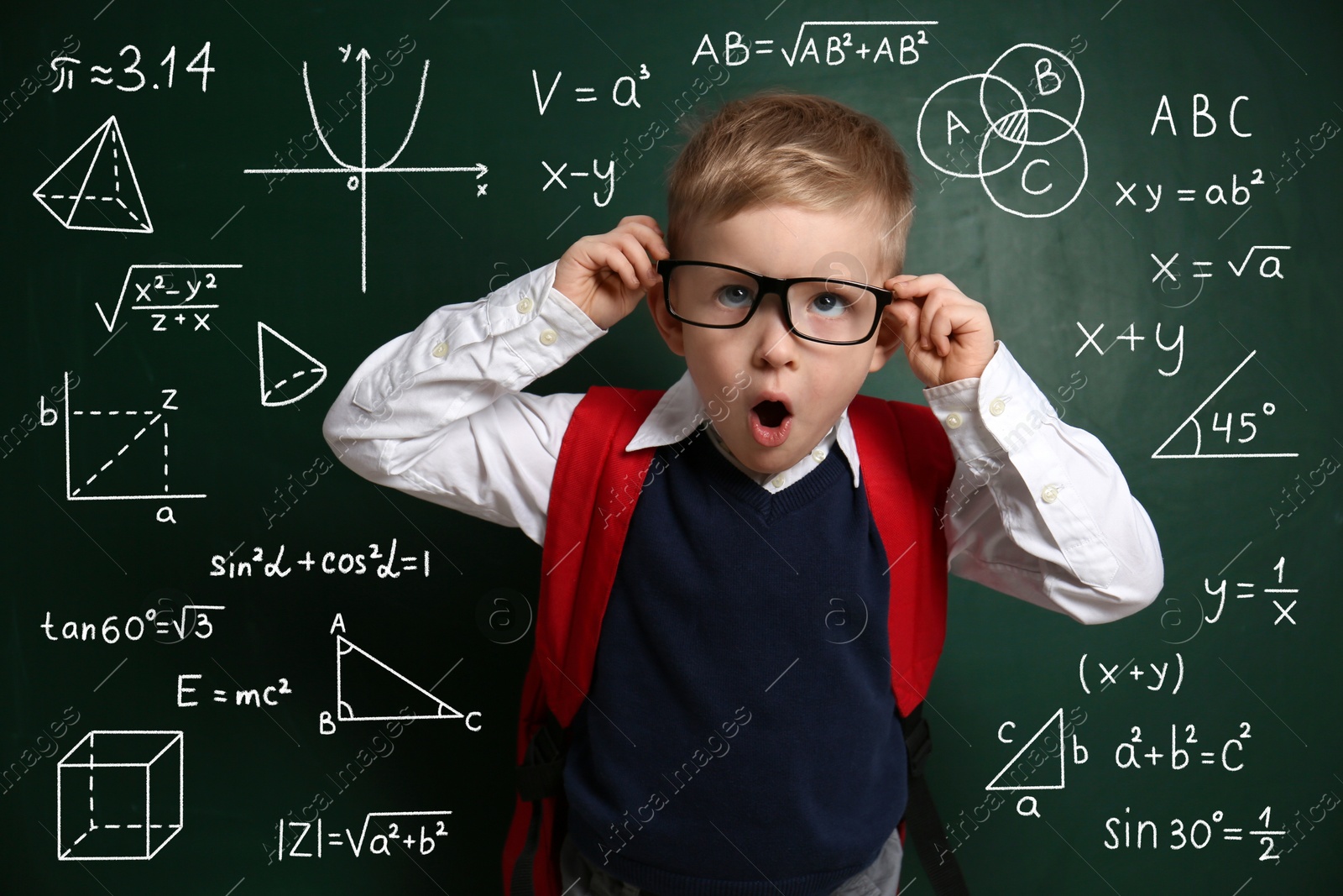 Amused child wearing eyeglasses near green chalkboard with formulas and drawings Image of Amused child wearing eyeglasses near green chalkboard with formulas and drawings