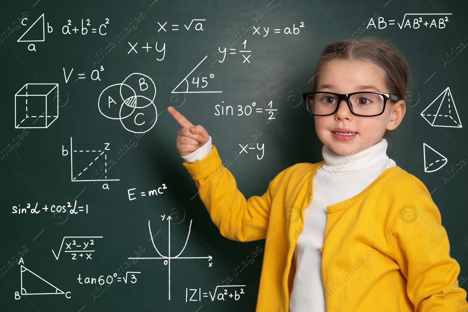 Image of Child pointing at green chalkboard with formulas and drawings