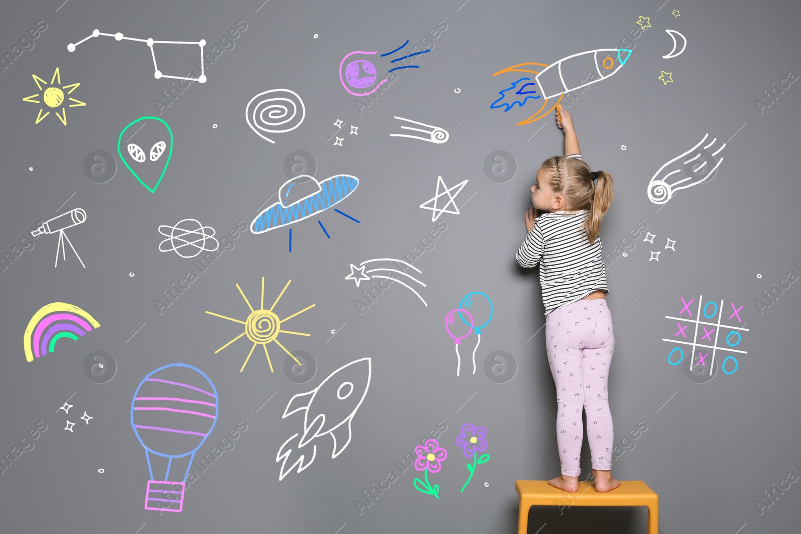 Image of Little child drawing on grey background with chalk