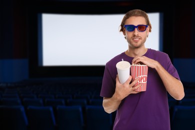 Image of Man with 3D glasses, beverage and popcorn in dark cinema