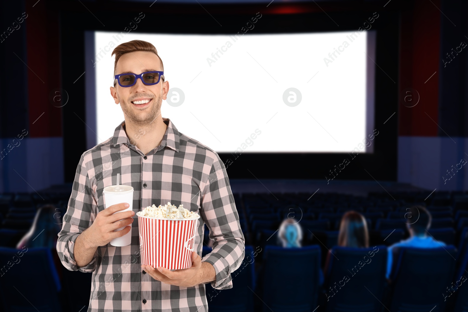 Image of Man with 3D glasses, beverage and popcorn in cinema