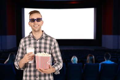 Image of Man with 3D glasses, beverage and popcorn in cinema
