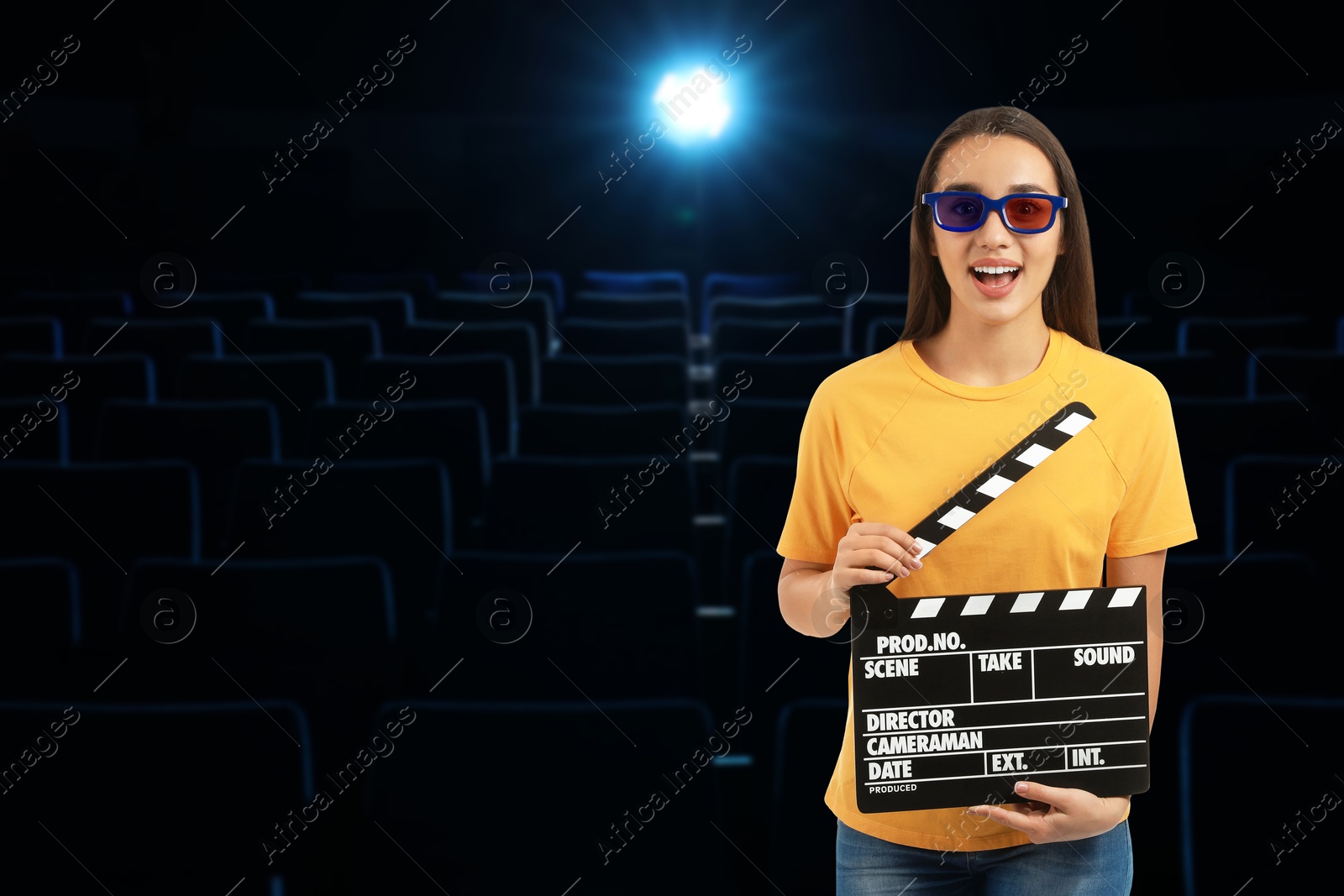 Image of Woman with 3D glasses and clapperboard in dark cinema