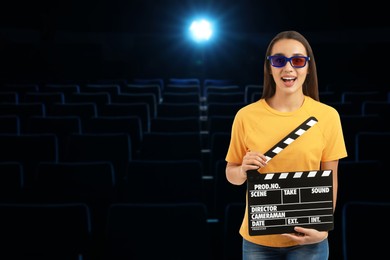 Image of Woman with 3D glasses and clapperboard in dark cinema