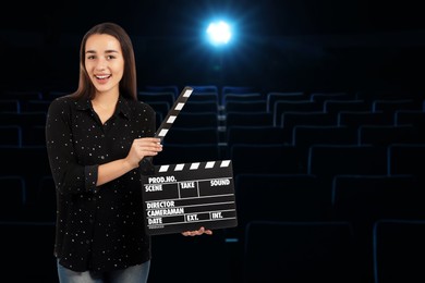 Image of Woman with mobie clapperboard in dark cinema