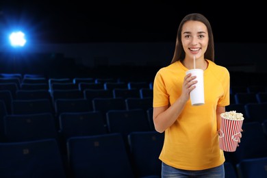 Image of Woman with beverage and popcorn in dark cinema