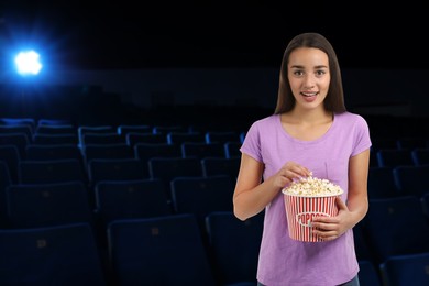 Image of Woman with big bucket of popcorn in dark cinema