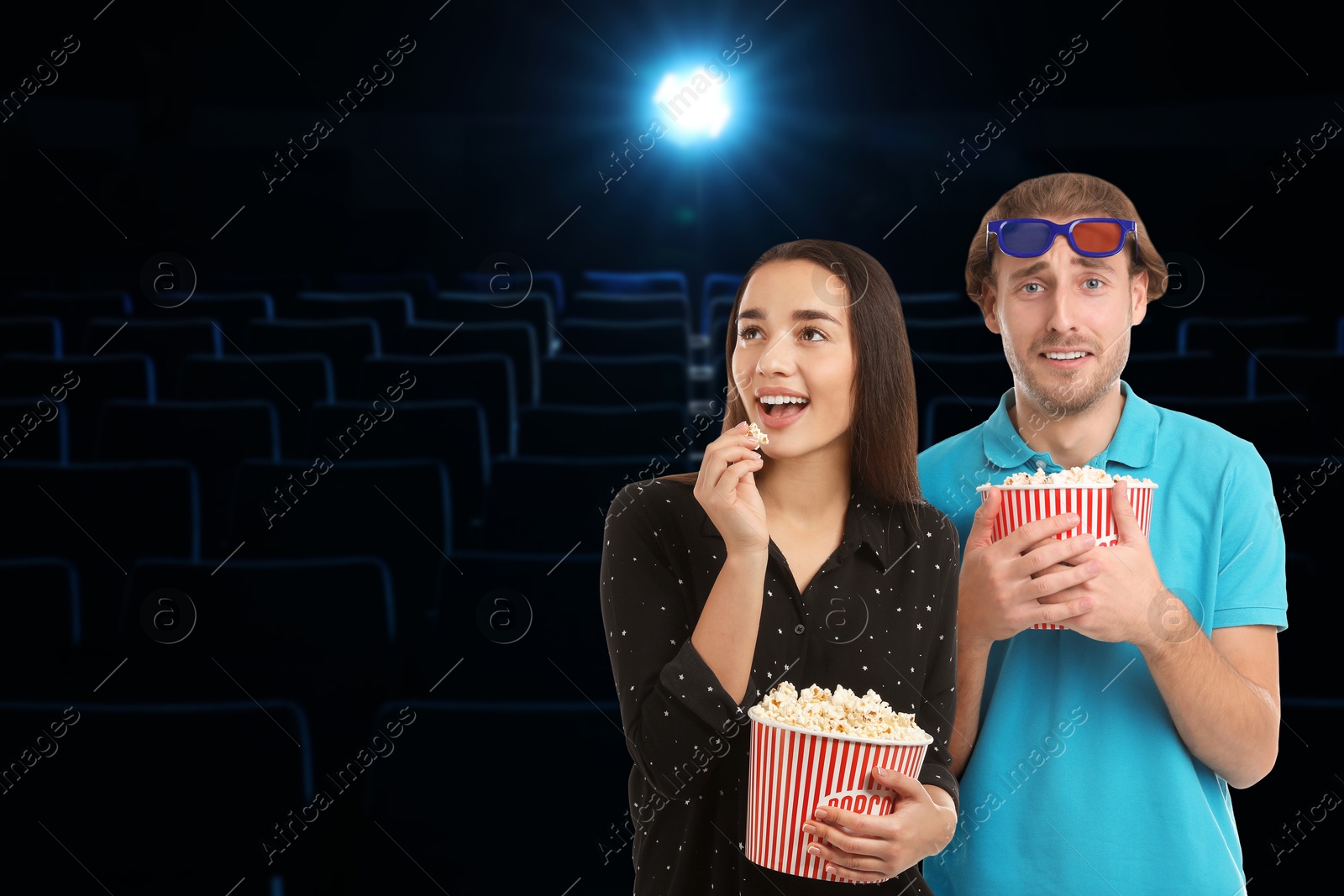 Image of Couple with buckets of popcorn in dark cinema