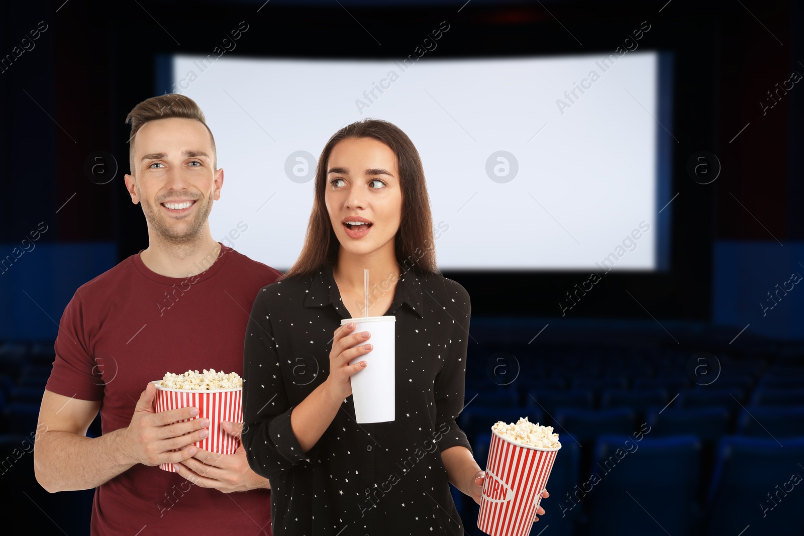Image of Couple with buckets of popcorn in dark cinema