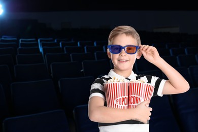 Image of Happy little boy with 3D glasses buckets of popcorn in dark cinema