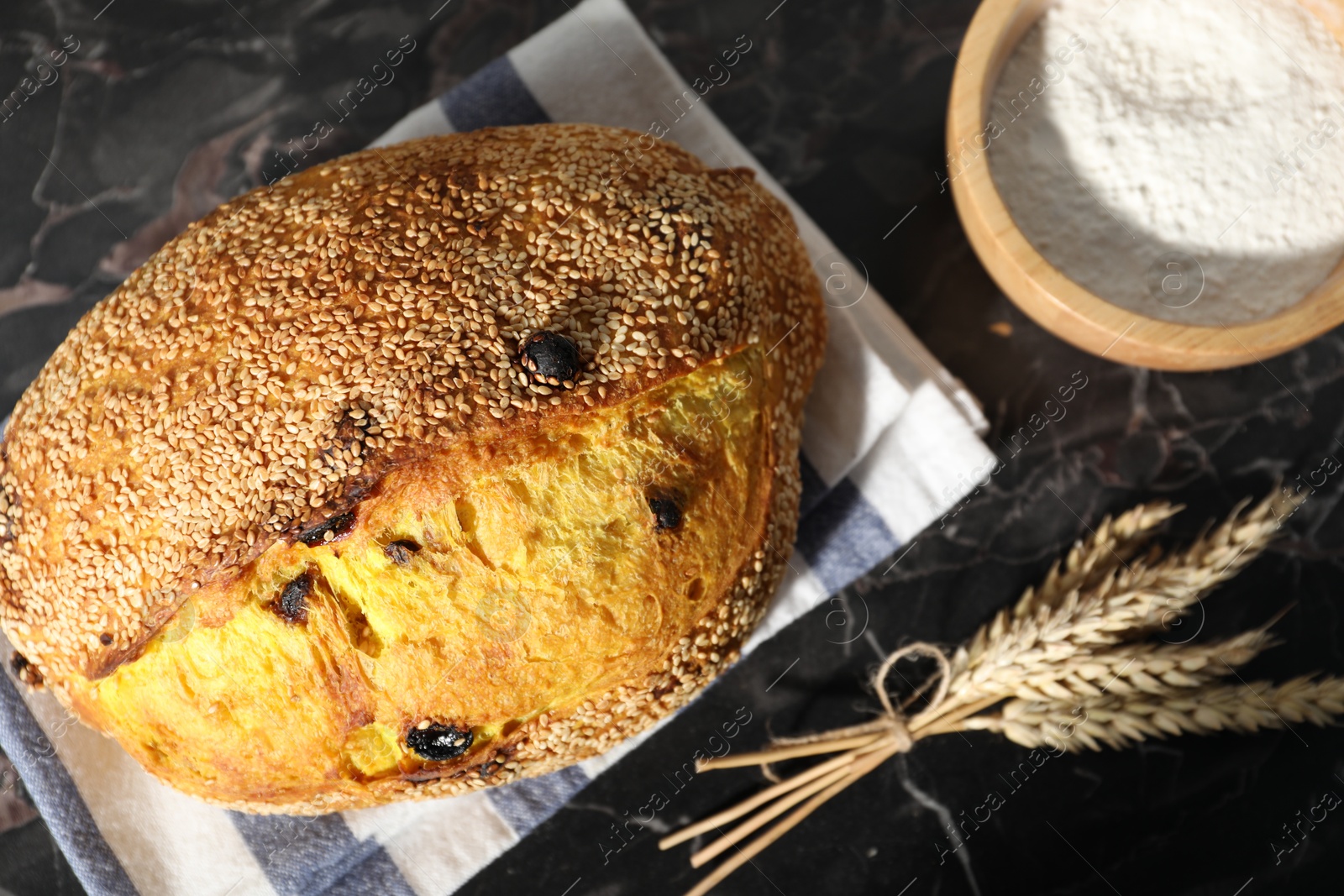 Loaf of fresh bread, flour and spikelets on black marble table, flat lay Photo of Loaf of fresh bread, flour and spikelets on black marble table, flat lay