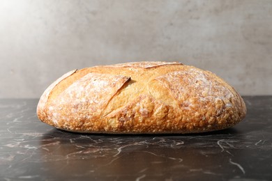 Photo of Loaf of fresh bread on black marble table, closeup