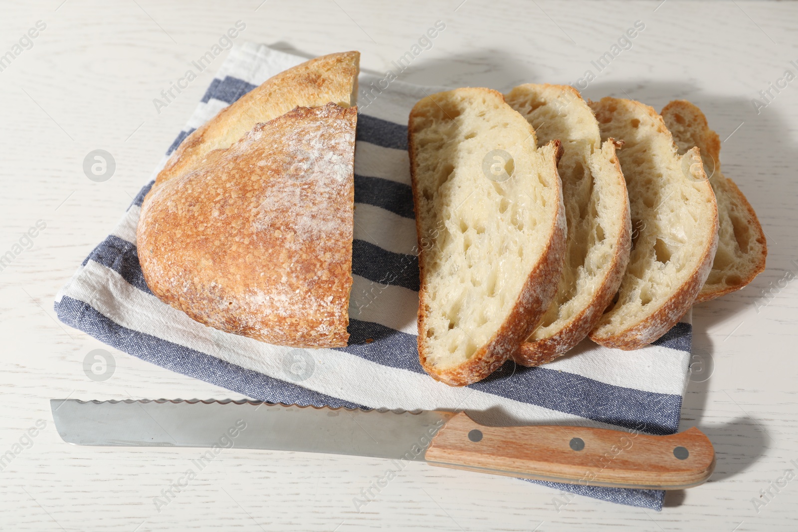 Loaf of fresh bread and knife on white wooden table, above view Photo of Loaf of fresh bread and knife on white wooden table, above view