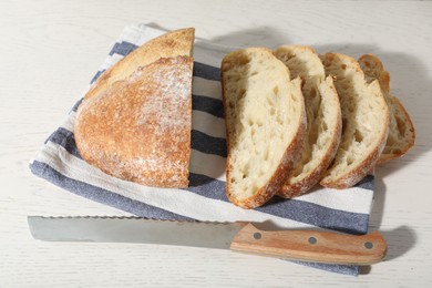 Photo of Loaf of fresh bread and knife on white wooden table, above view