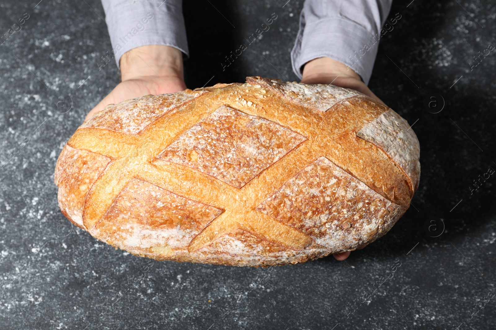 Baker with loaf of fresh bread at grey textured table, top view Photo of Baker with loaf of fresh bread at grey textured table, top view