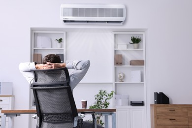 Image of Worker under air conditioner in office. Keeping comfortable temperature