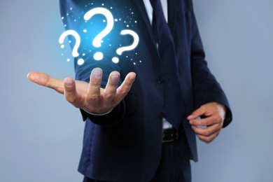 Image of Businessman holding question marks against grey background, closeup