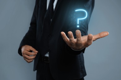 Image of Businessman holding question mark against grey background, closeup