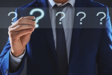 Image of Businessman touching question mark on virtual screen against dark background, closeup