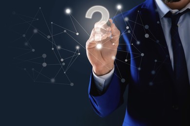 Image of Businessman touching question mark on virtual screen against dark background, closeup
