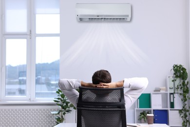 Image of Worker under air conditioner in office. Keeping comfortable temperature