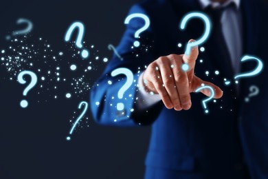 Image of Businessman touching virtual question mark against dark background, closeup