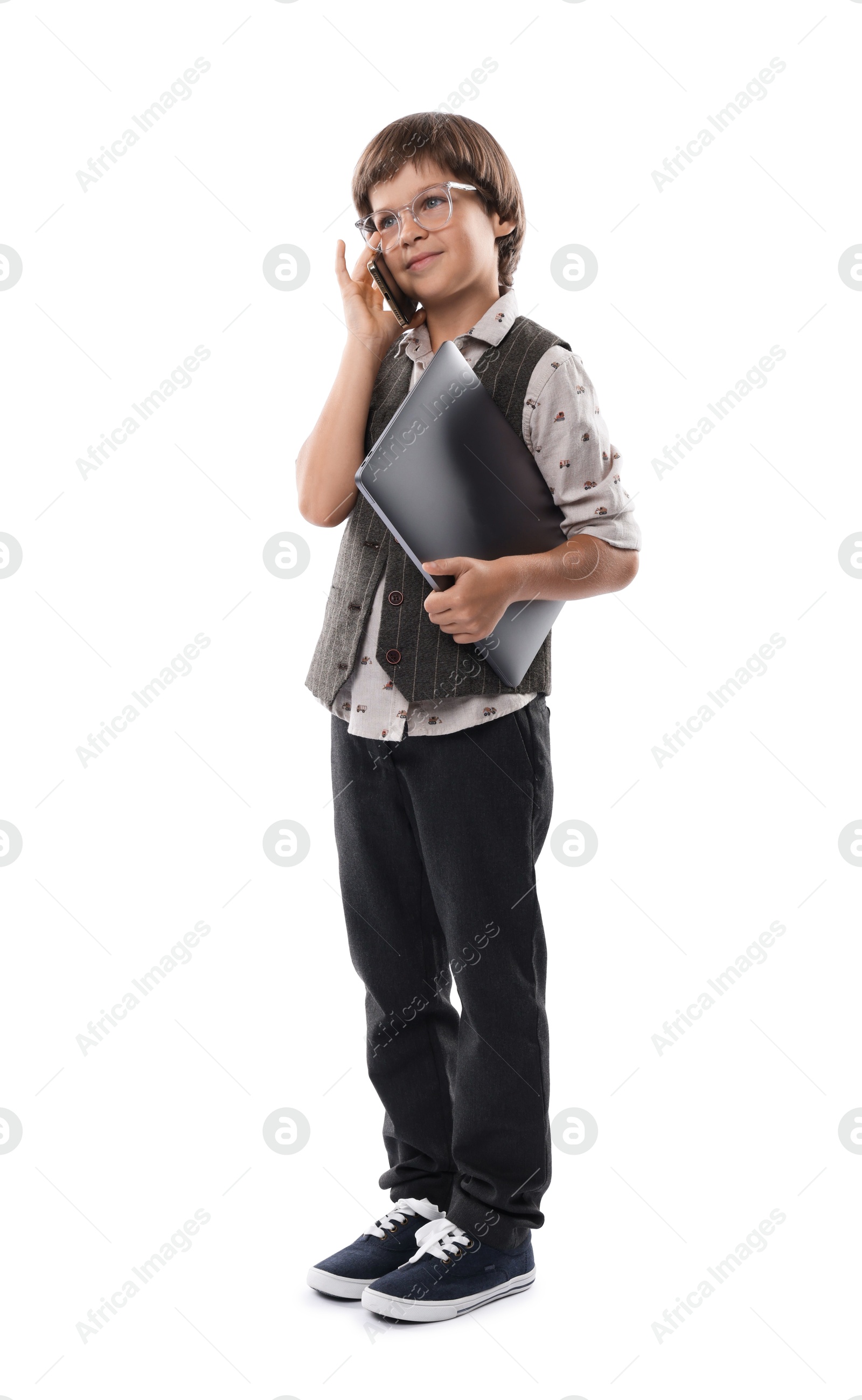 Photo of Choice of profession. Little boy in glasses talking by smartphone pretending to work with laptop on white background