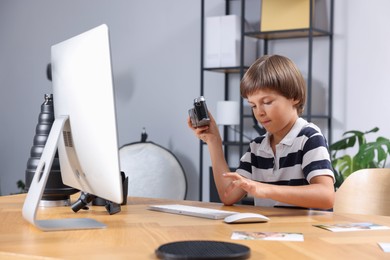 Photo of Choice of profession. Little boy with camera pretending to be photographer at wooden table in studio