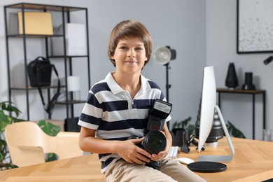 Photo of Choice of profession. Little boy with camera pretending to be photographer on wooden table in studio