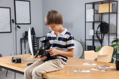 Photo of Choice of profession. Little boy with camera pretending to be photographer on wooden table in studio