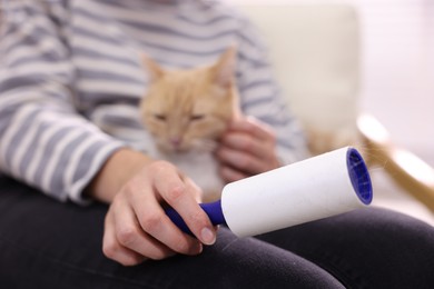 Photo of Woman with lint roller and her cat at home, selective focus