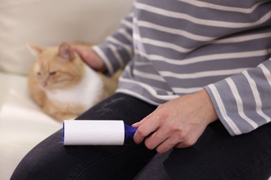 Photo of Woman with lint roller stroking her cat on armchair, closeup