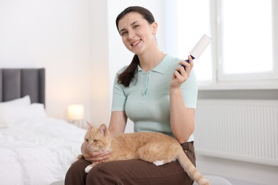 Photo of Smiling woman with lint roller and her cat in bedroom