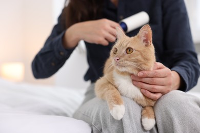 Photo of Woman with lint roller removing pet's hair from clothes and her cat on bed at home, closeup. Space for text