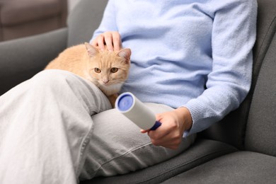 Photo of Woman with lint roller stroking her cat on sofa, closeup