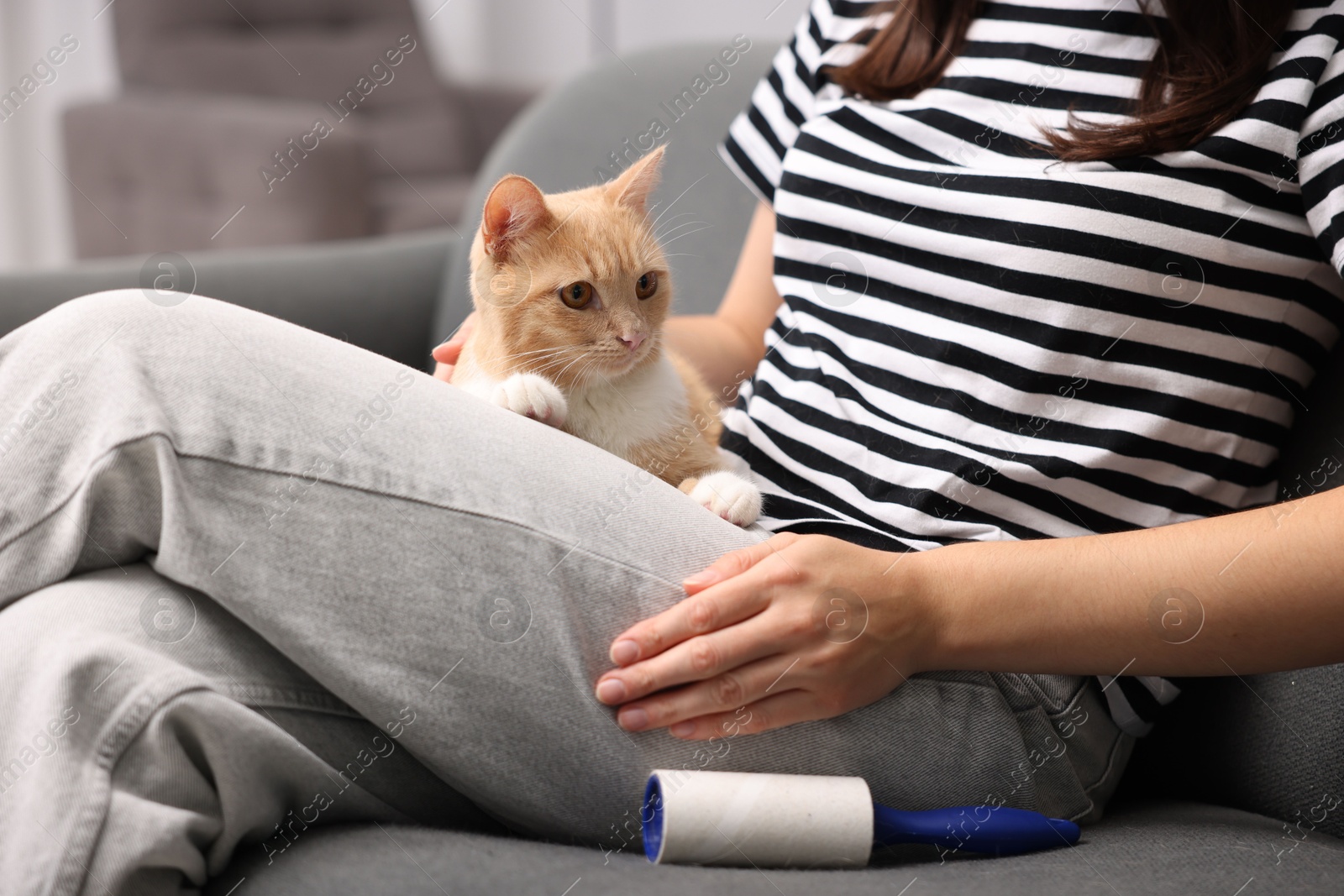 Photo of Woman with lint roller and her cat on sofa at home, closeup