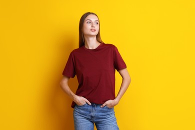 Photo of Woman wearing stylish burgundy t-shirt on yellow background