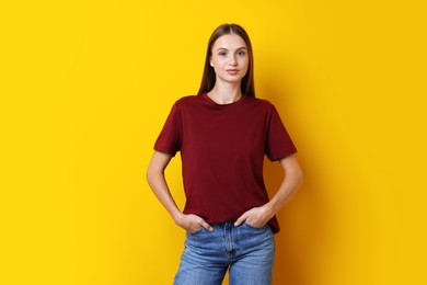 Photo of Woman wearing stylish burgundy t-shirt on yellow background