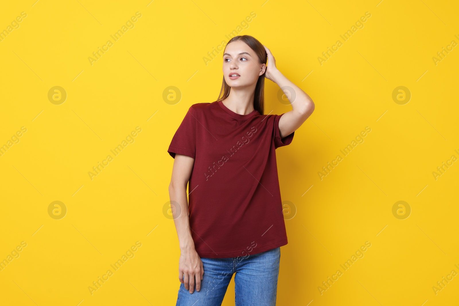 Photo of Woman wearing stylish burgundy t-shirt on yellow background
