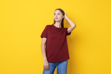 Photo of Woman wearing stylish burgundy t-shirt on yellow background
