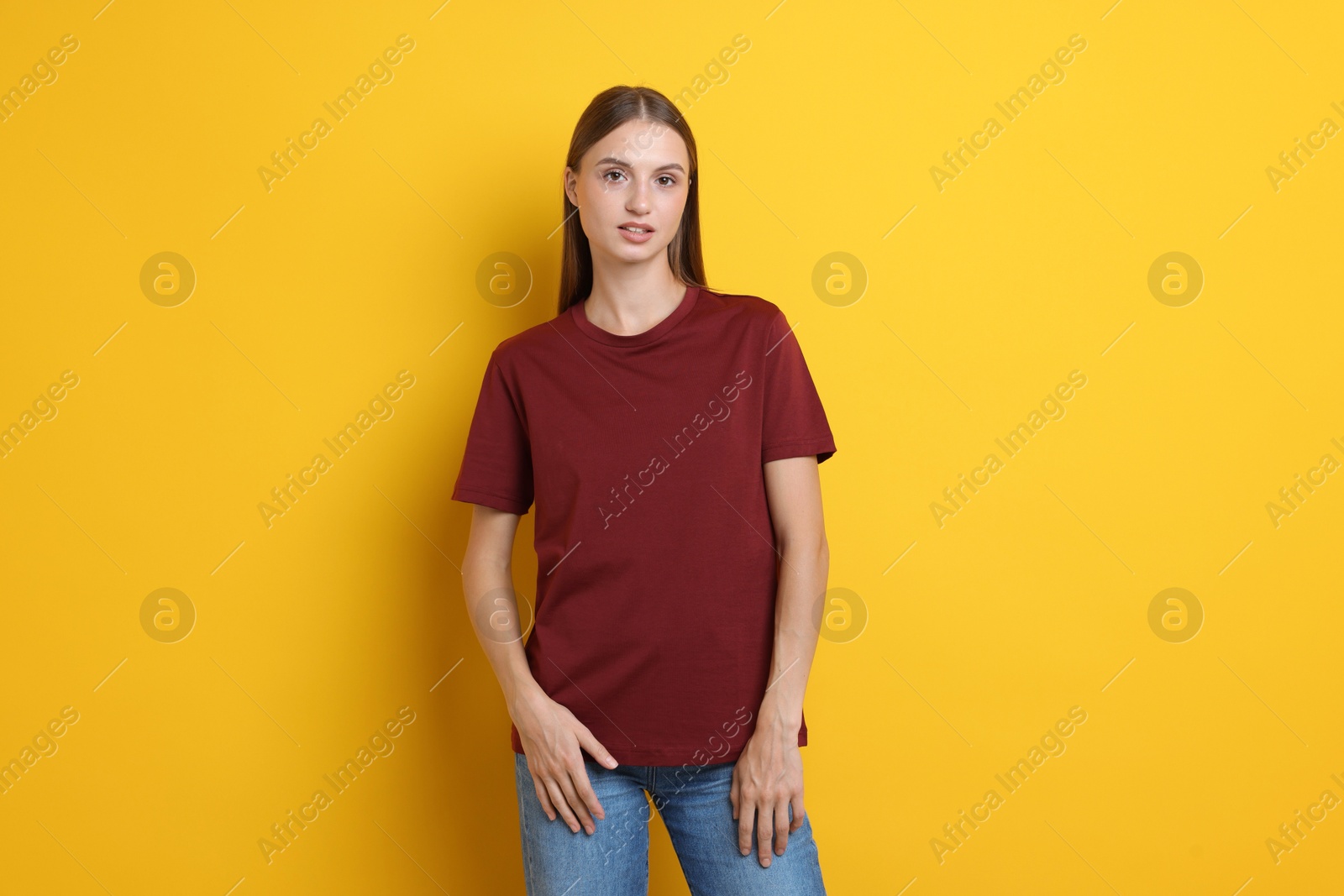 Photo of Woman wearing stylish burgundy t-shirt on yellow background